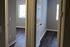Inviting hallway view showcasing beautiful dark wood floors leading to well-lit rooms with large windows.