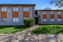 Charming mid-century modern apartment building with vibrant orange accents and lush green landscaping.