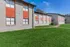 Charming apartment exterior with vibrant orange accents and lush green lawns, offering a welcoming and stylish living space.