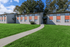 Charming residential building with bright facades, surrounded by lush green lawns and a welcoming pathway.