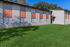 Charming apartment building with a modern facade and lush green lawn under a clear blue sky.