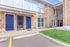 Charming apartment exterior with modern blue doors, brick facade, and lush green lawn, offering a warm welcome.