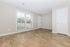 Bright and inviting living space with expansive wood flooring and large window overlooking lush greenery.