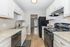 Modern kitchen with sleek black appliances, white cabinetry, and elegant countertops, leading to a bright dining area.