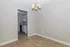 Inviting dining area with elegant chandelier light fixture and open view to a modern kitchen featuring sleek cabinetry and updated finishes, accented by warm wood flooring.