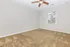 Spacious bedroom with plush carpet, modern ceiling fan, and large window offering ample natural light.