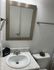 Modern bathroom with a sleek framed mirror, elegant sink, and decorative accents. Bright and inviting space.