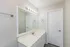 Elegant bathroom with a large mirror, sleek vanity, and modern lighting.