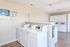 Bright and modern laundry room with top-loading washers and stacked dryers, featuring convenient payment options and sleek wood flooring.