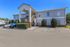 Charming two-story apartment building with a welcoming entrance, ample parking, and well-maintained landscaping under a clear blue sky.