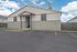 Modern residential building exterior featuring a welcoming entrance and spacious parking area under a clear blue sky.
