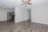 Bright open-plan living space with sleek hardwood floors, modern ceiling fan, and stainless steel kitchen appliances.