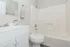 Bright and modern bathroom featuring sleek white cabinetry, a polished vanity, and a pristine bathtub.