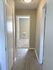 Inviting apartment hallway with sleek wood flooring leading to a cozy carpeted room, bathed in warm natural light.