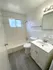 Bright and modern bathroom featuring a sleek vanity, bathtub, and elegant light fixtures with ample natural light.