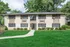 Charming two-story apartment building surrounded by lush greenery, offering a serene and inviting atmosphere.