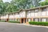 Charming two-story townhouse with elegant brick facade and lush greenery, offering a serene residential vibe.