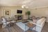 Inviting living room with modern decor, featuring a cozy stone fireplace, elegant dining area, and comfortable seating on warm wood flooring.
