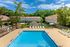Charming apartment community with inviting swimming pool, surrounded by lush greenery and cozy residential buildings.