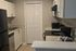 Elegant modern kitchen with sleek white cabinetry, marble countertops, and stainless steel appliances in a cozy layout.