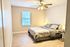 Cozy bedroom with modern decor featuring a comfortable bed, stylish lamps, and soft natural lighting from a window with blinds.