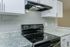 Modern kitchen with sleek granite countertops, elegant white cabinetry, and a high-end black electric stove, ideal for stylish cooking.
