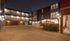 Charming apartment complex courtyard at night with warm lighting, modern architecture, and inviting outdoor space.
