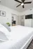 Bright, elegant bedroom with a modern ceiling fan, crisp white bedding, and sleek decor, offering a peaceful and stylish retreat.