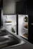 Modern kitchen view with a sleek black refrigerator stocked with fresh produce and beverages, reflecting stylish design and functionality.