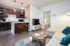 Modern apartment living area featuring an open-concept kitchen with dark wood cabinets, cozy seating, and stylish pendant lighting.