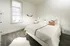 Bright and cozy bedroom with a modern design, featuring a plush bed, elegant wooden flooring, and abundant natural light.