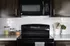 Sleek modern kitchen with stylish black appliances, glossy white subway tiles, and elegant dark cabinetry, perfect for culinary creativity.
