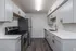 Modern kitchen with sleek stainless steel appliances, bright white cabinetry, and elegant dark wood flooring.