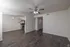 Modern apartment interior featuring elegant wood flooring, a ceiling fan, and a sleek kitchen with stainless steel appliances.