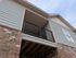 Charming exterior of an apartment with modern siding, a cozy balcony, and elegant brickwork under a vast blue sky.