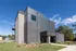 Modern leasing office with sleek brick and metal facade under clear blue skies, surrounded by lush greenery.