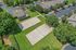Aerial view of charming apartment complex with lush landscaping, featuring two volleyball courts, ample parking, and surrounding verdant trees.
