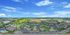 Breathtaking aerial view of a vibrant residential community with modern homes, abundant green spaces, and a shimmering pool under a clear blue sky.