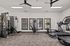 Modern fitness center with state-of-the-art equipment, large windows, and ceiling fans for a bright and airy workout environment.
