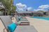 Inviting poolside area with stylish lounge chairs and vibrant turquoise cushions, perfect for relaxation under a sunny sky.