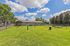 Expansive grassy dog park with agility equipment, shaded seating area, and beautiful blue skies&mdash;ideal for pet-friendly living.