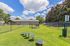 Inviting outdoor space featuring a lush green dog park under a bright blue sky, equipped with agility equipment and fenced for safety.