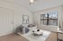 Bright and inviting living room with large window, cozy sofa, stylish decor, and modern ceiling fan.