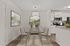 Modern dining area with elegant glass table, chic chairs, and contemporary artwork, seamlessly connected to a sleek kitchen with stainless appliances.