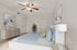 Inviting bedroom with stylish decor, featuring a plush bed with blue and green pillows, modern dresser, and elegant ceiling fan.