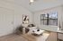 Bright and cozy living room featuring a stylish beige sofa, modern art, and large window offering natural light.