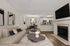 Chic, open-concept living area featuring cozy sofa, modern dining set, and sleek kitchen with stainless steel appliances, accented by contemporary art and a stylish fireplace.