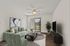Chic living room with stylish mint green sofa, modern decor, and elegant glass doors opening to a scenic view.
