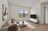 Bright and inviting living room with modern decor, featuring a large window, stylish couch, and sleek TV unit.