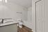 Bright and modern bathroom featuring a sleek granite countertop, elegant white cabinetry, and a spacious bathtub with hardwood floors.